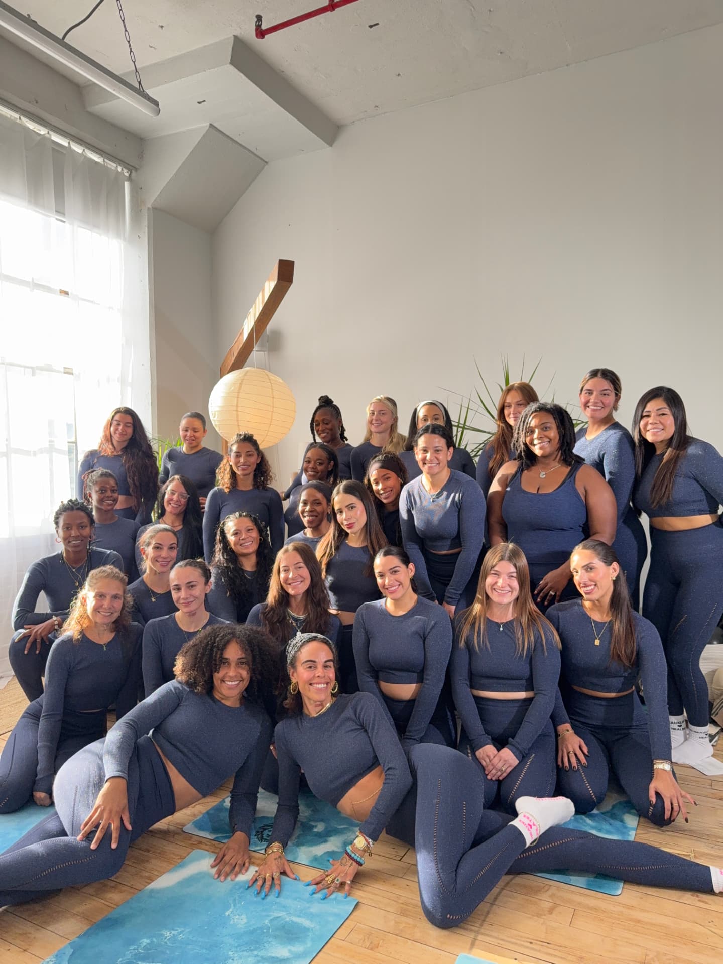 A Pilates Plug cohort in matching training kit standing together in the studio