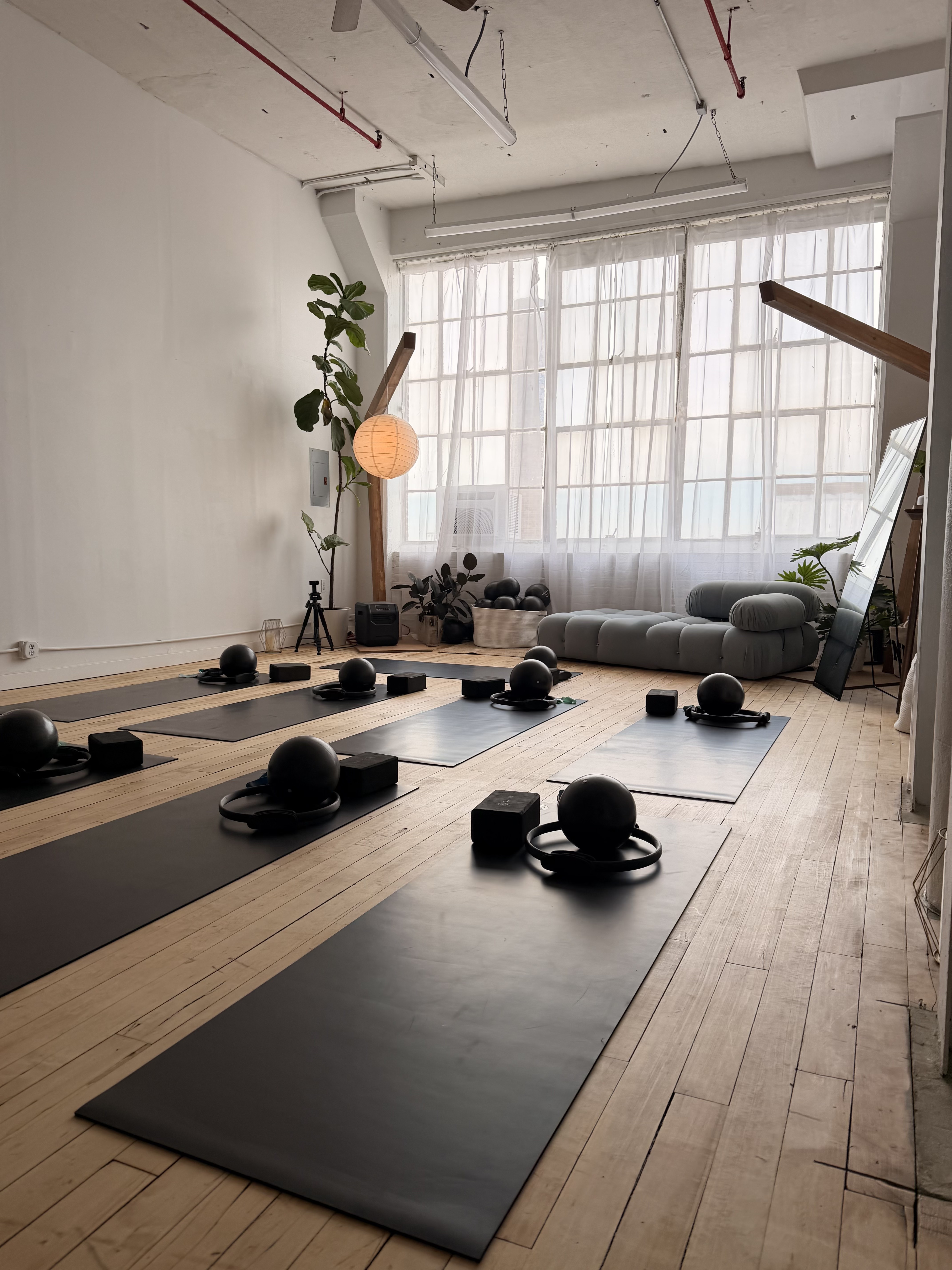 The Soul Therapy Studios training room with mats, blocks and balls set out beneath tall curtained windows